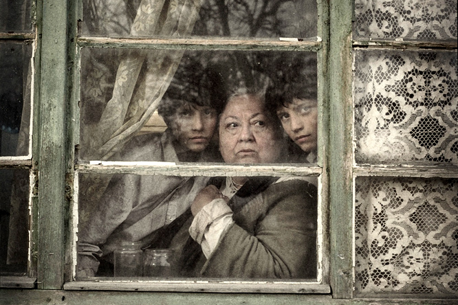 La abuela y los gemelos asomados a una ventana. Fotograma de "El gran cuaderno" (2013), de János Szász, adaptación de la obra de Agota Kristof