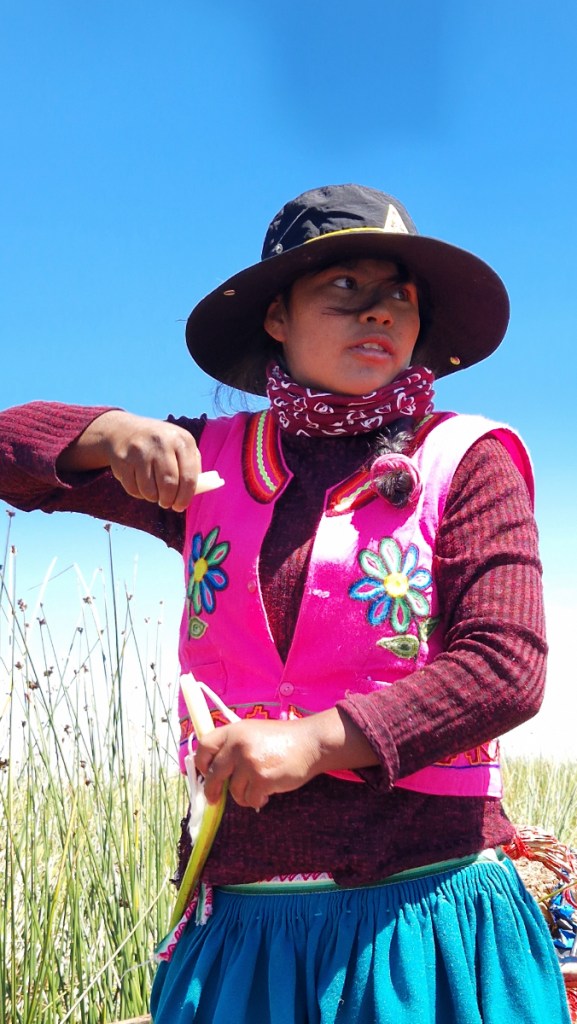 Una chica uro sostiene un trozo pelado de totora